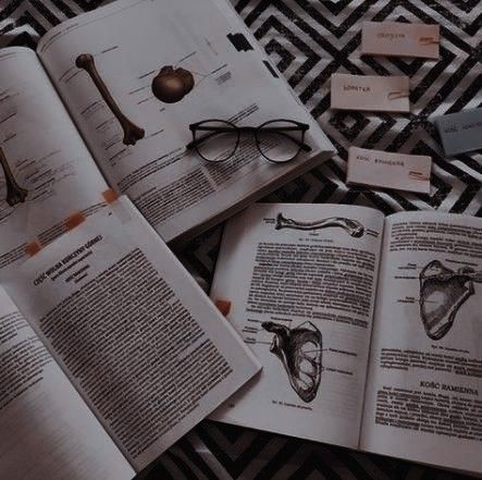 an open book sitting on top of a black and white floor covered in books next to glasses