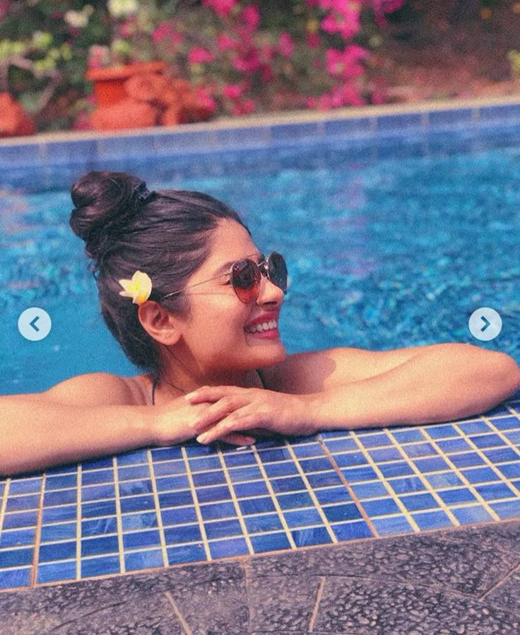 a woman is smiling while sitting in the pool