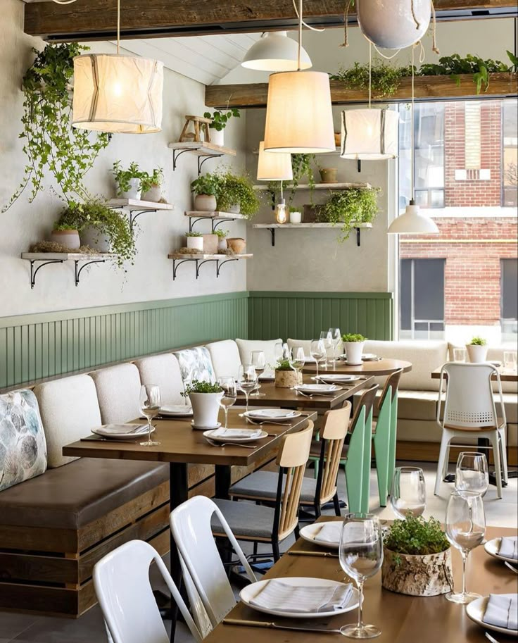 a restaurant with wooden tables and white chairs, plants on the wall above them are hanging from shelves