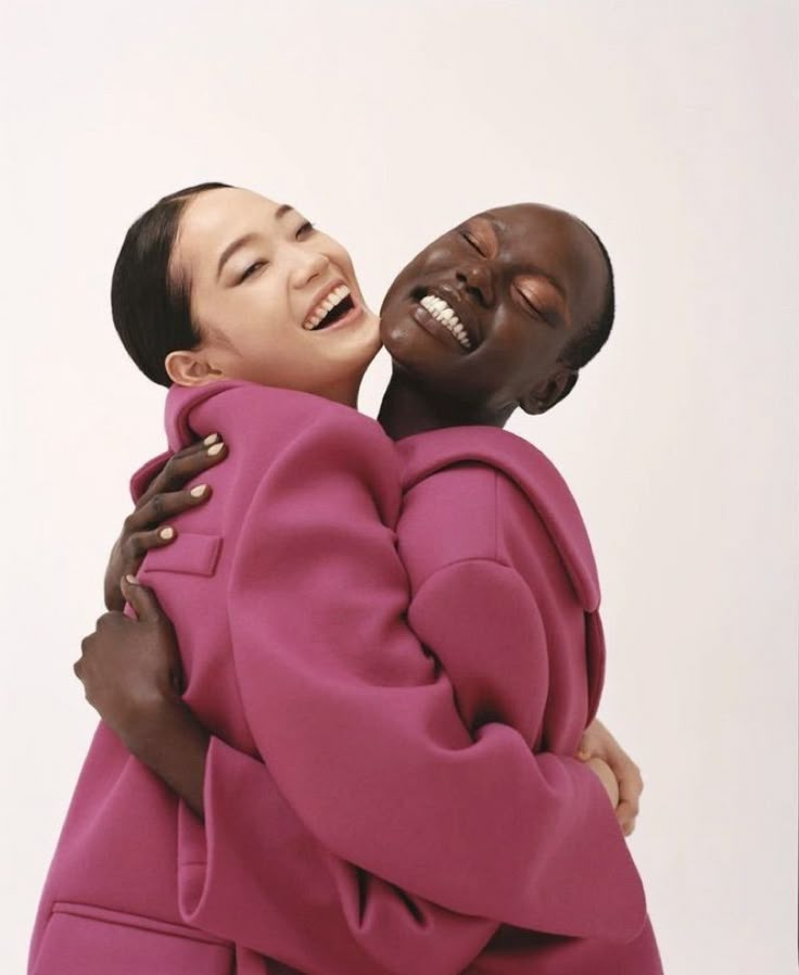 two people are hugging each other with their heads close to one another, both wearing pink