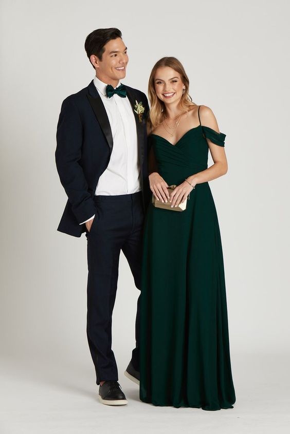 a man in a tuxedo standing next to a woman in a green dress