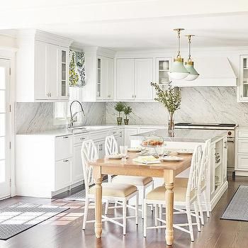 a kitchen filled with white cabinets and wooden flooring next to a dining room table