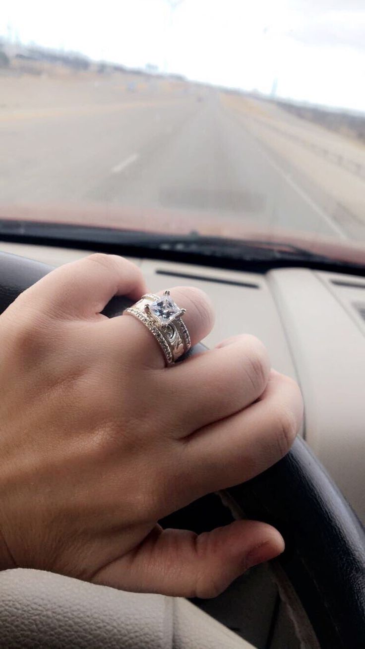 a woman's hand on the steering wheel of a car with a diamond ring