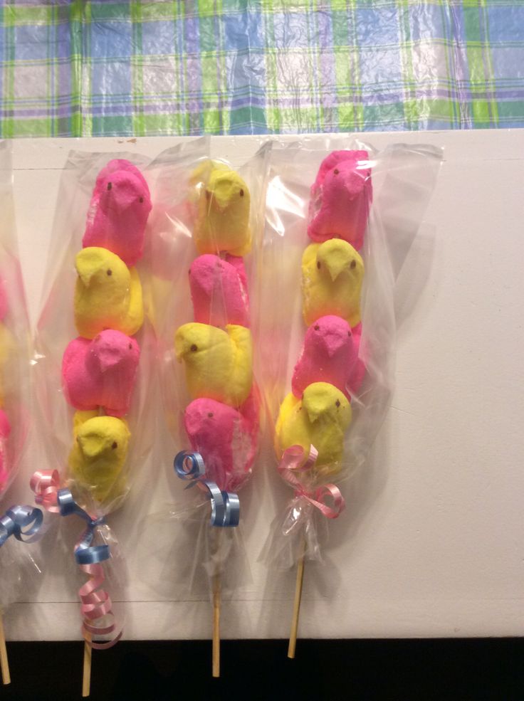 four lollipops with yellow and pink frosting on them in plastic bags