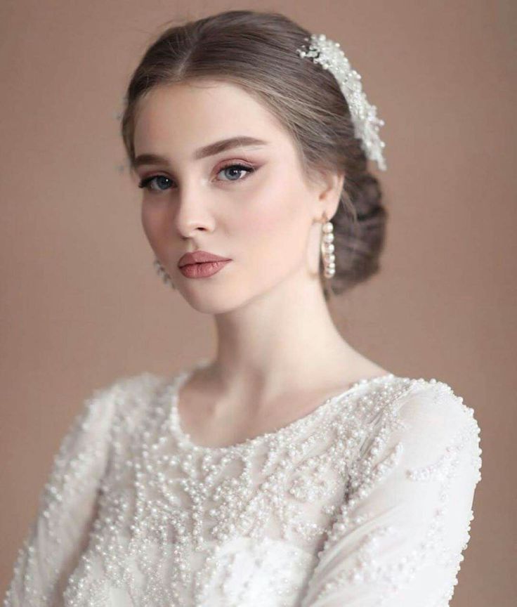 a woman in a white dress with pearls on her head