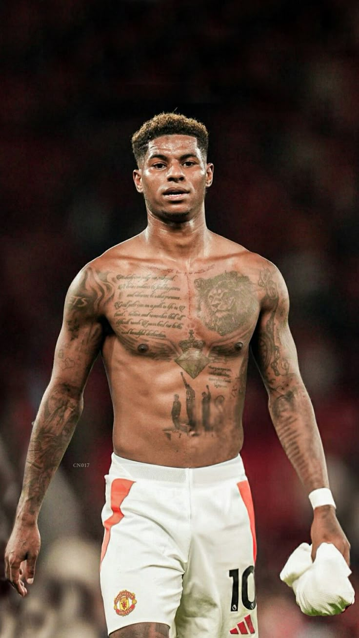 a man with tattoos on his chest and no shirt holding a soccer ball in his hand