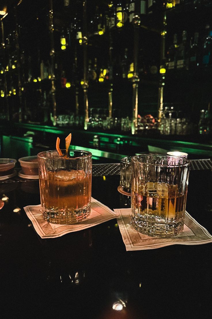 two glasses are sitting on napkins next to each other in front of a cityscape