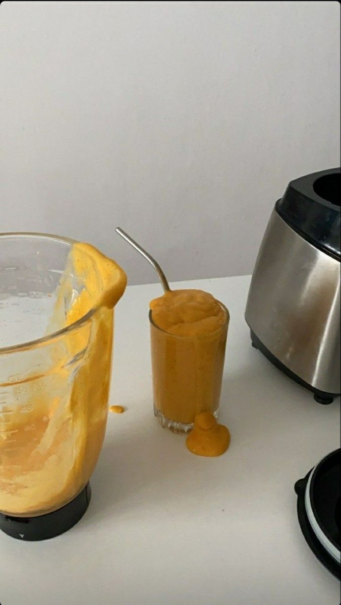 a blender filled with yellow liquid next to an orange smoothie