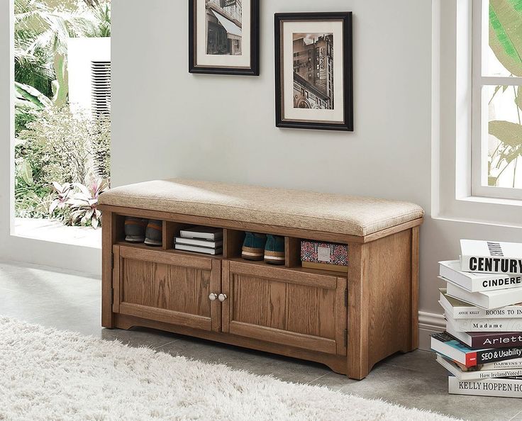 a wooden bench sitting in the middle of a living room next to a pile of books