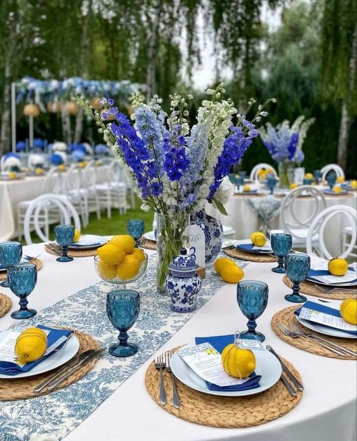 the table is set with blue and white plates, silverware, and lemons