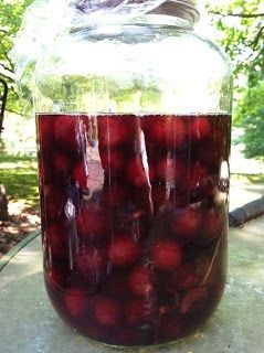 a jar filled with cherries sitting on top of a cement table next to trees