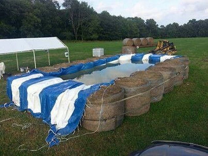 an inflatable swimming pool is being constructed with hay bales and tarps