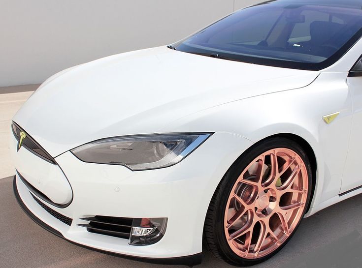 a white car with pink rims parked in a parking lot