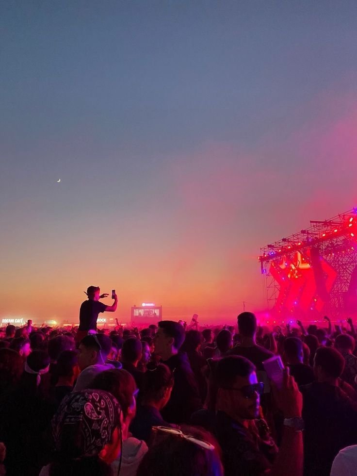 a man standing on top of a stage in front of a crowd at night time