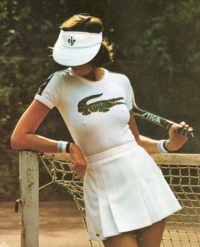 a woman holding a tennis racquet standing next to a net on a tennis court