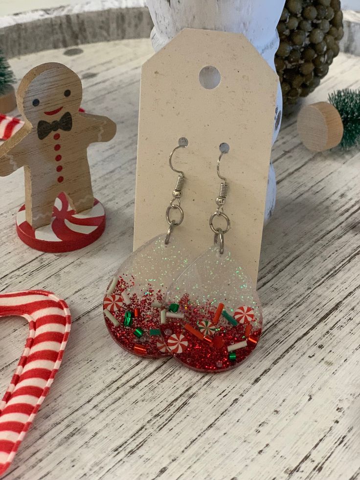 some christmas decorations are sitting on a table next to a pair of earrings and a candy cane