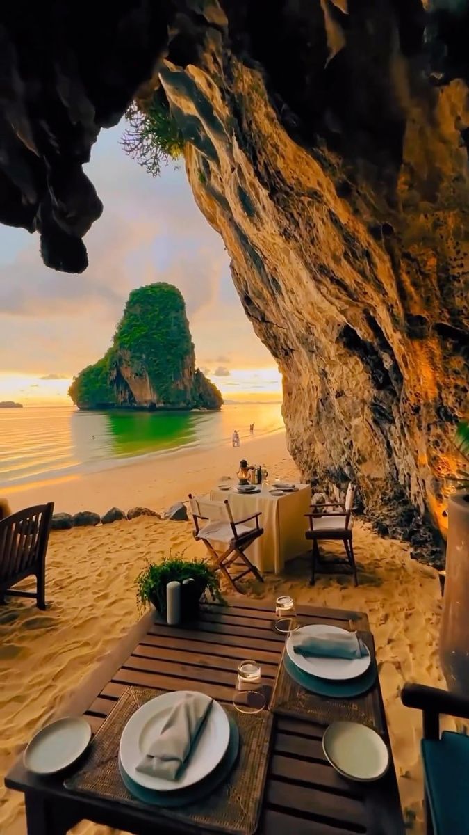 an outdoor dining area on the beach with tables and chairs set up for two people