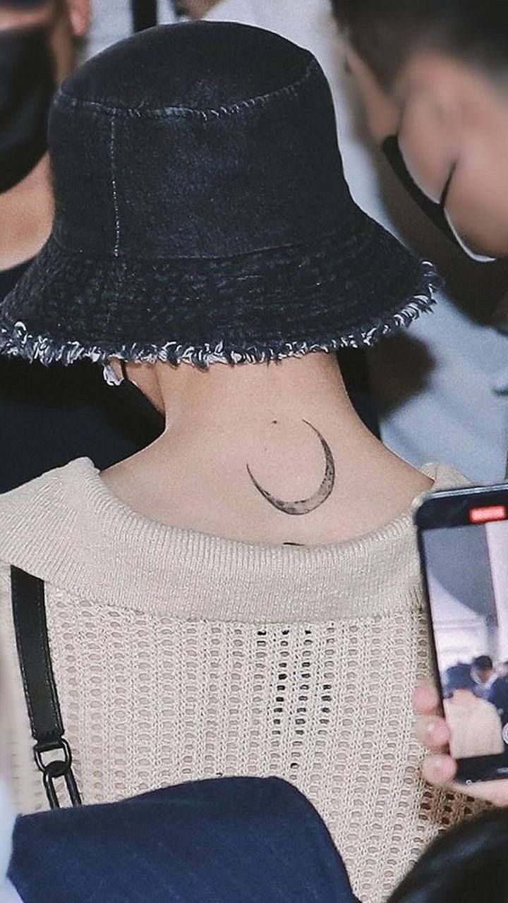 a woman with a small crescent tattoo on her upper back neck, holding a cell phone