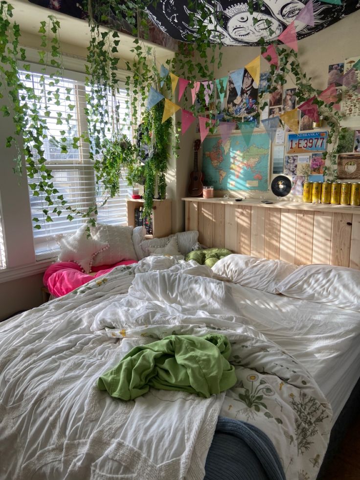 an unmade bed in a bedroom with plants hanging from the ceiling and decorations on the walls