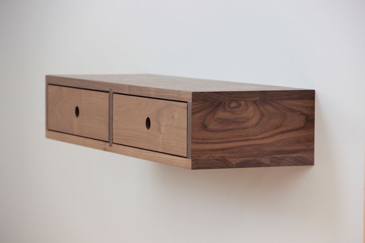 a wooden shelf with two drawers mounted on it's side against a white wall