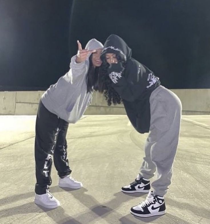 two people standing in the middle of an empty parking lot with one person wearing a hoodie