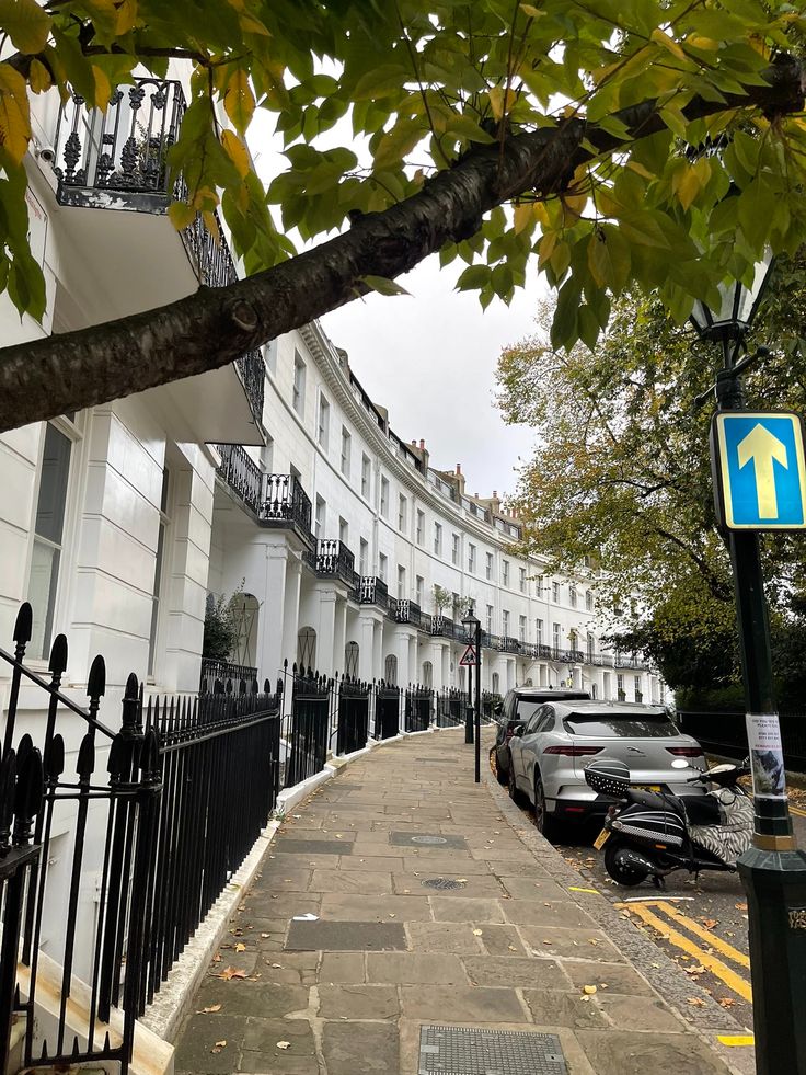 a street with cars parked on the side of it next to a tall white building