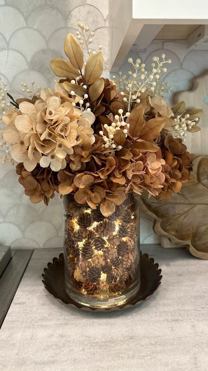 a vase filled with lots of flowers on top of a counter