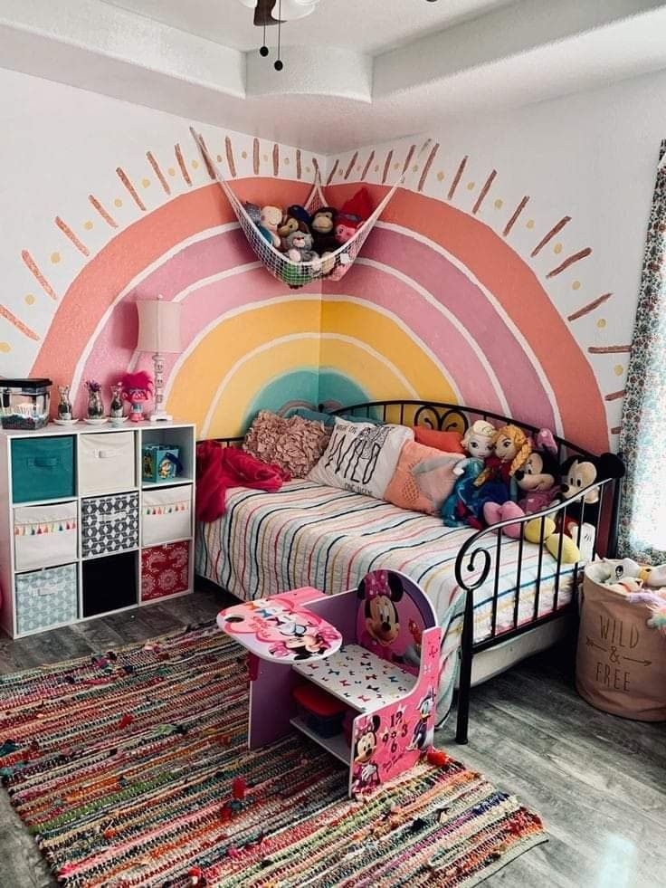 a child's bedroom decorated in pink, orange, and yellow with a rainbow theme