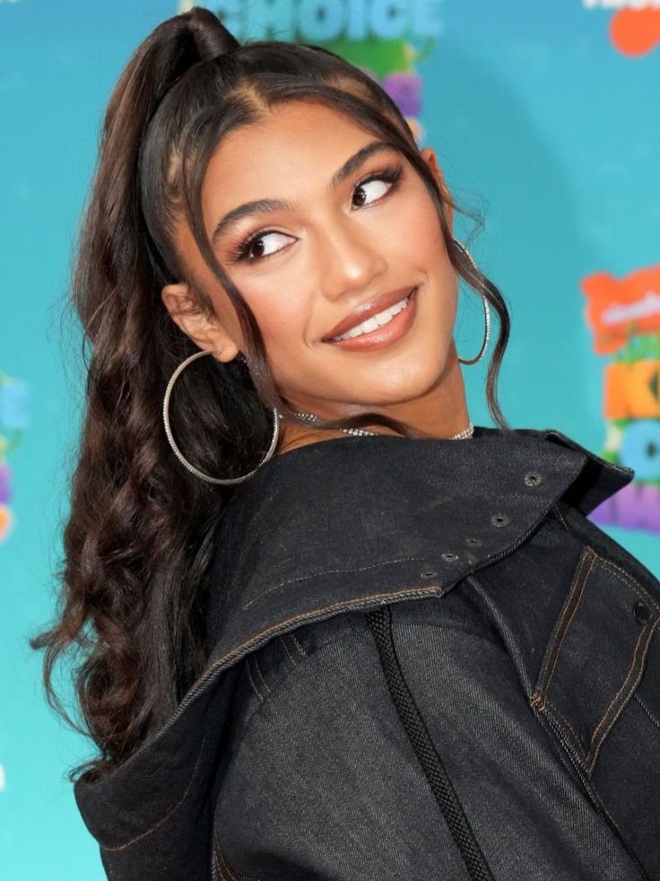 a close up of a person wearing large hoop earrings and a black top with an earring