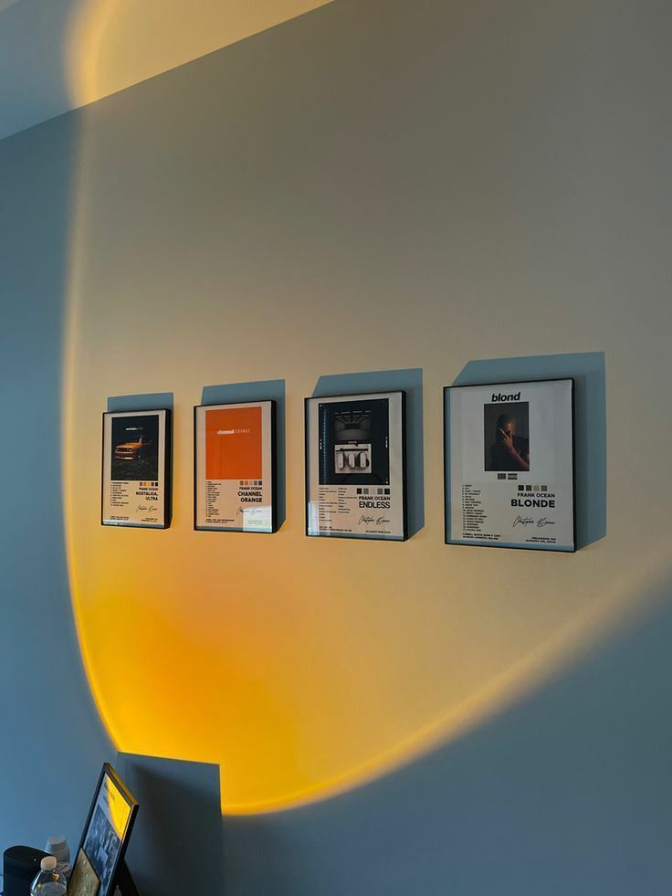 a laptop computer sitting on top of a desk next to three framed pictures hanging on the wall