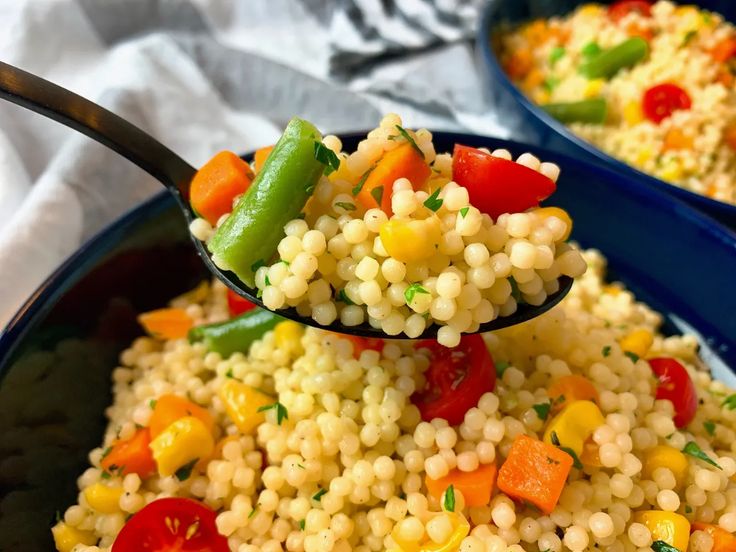 a spoon full of couscous with vegetables on it