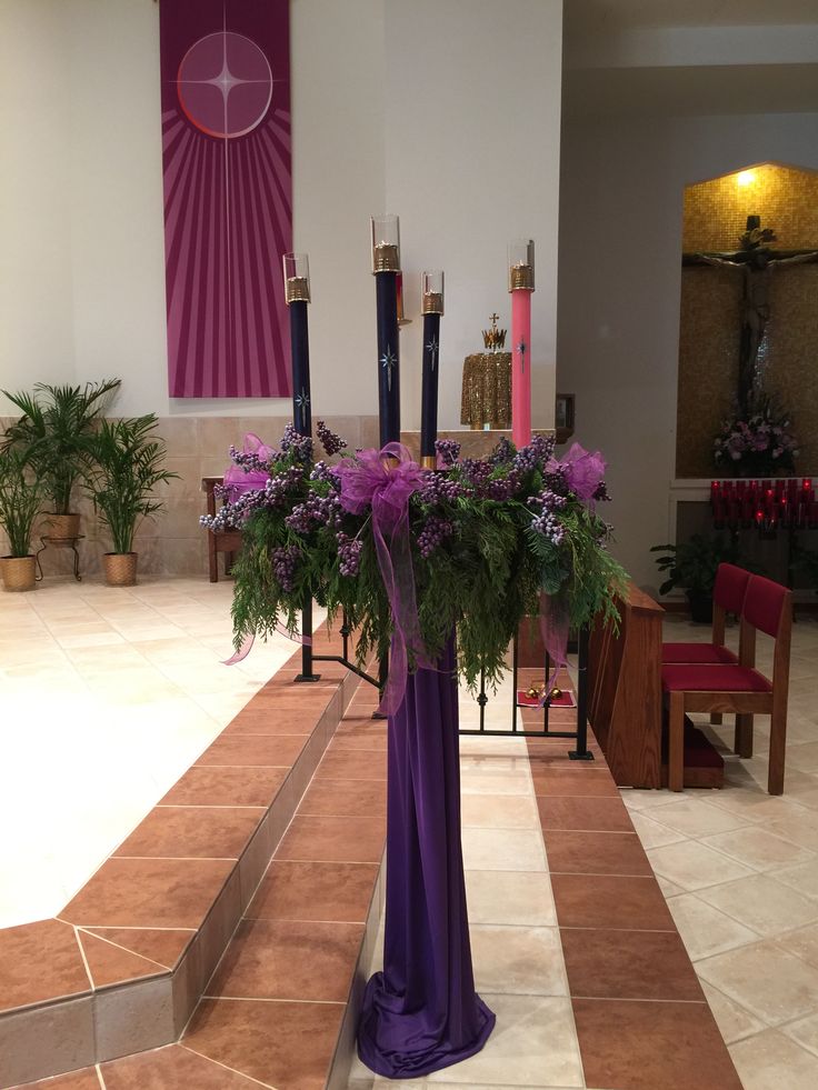 a vase with flowers and candles in it on the floor next to a table filled with chairs