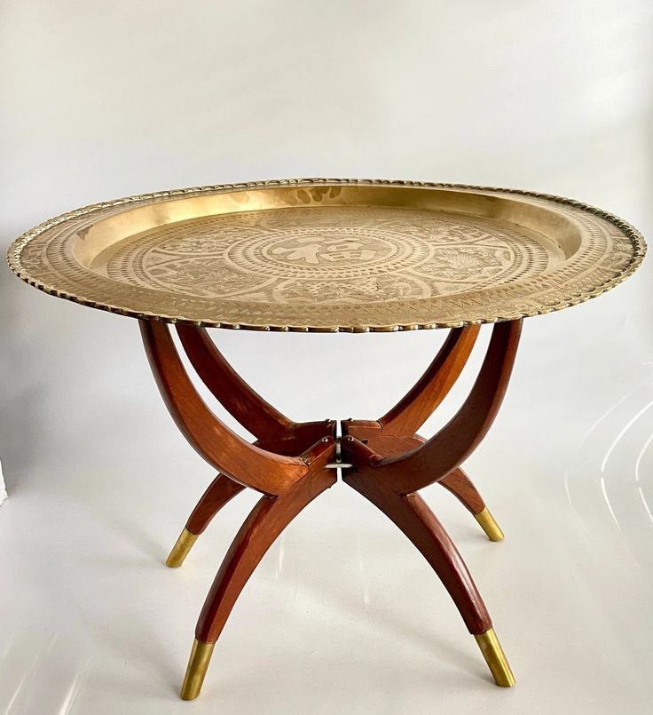 a wooden table with a metal tray on it's legs and gold trim around the edge