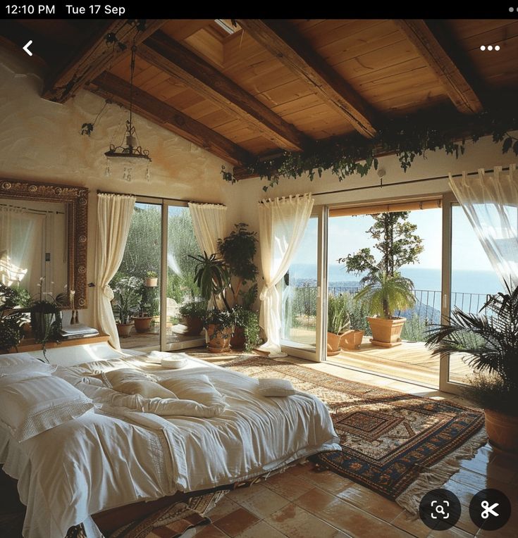 a bed room with a neatly made bed and lots of windows overlooking the ocean on a sunny day