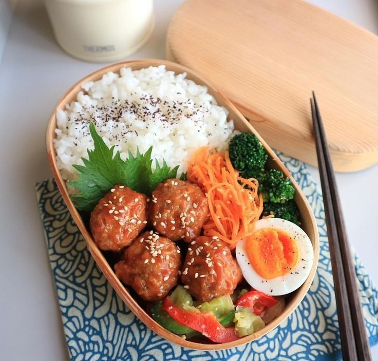 a bowl filled with rice, meat and vegetables next to chopsticks