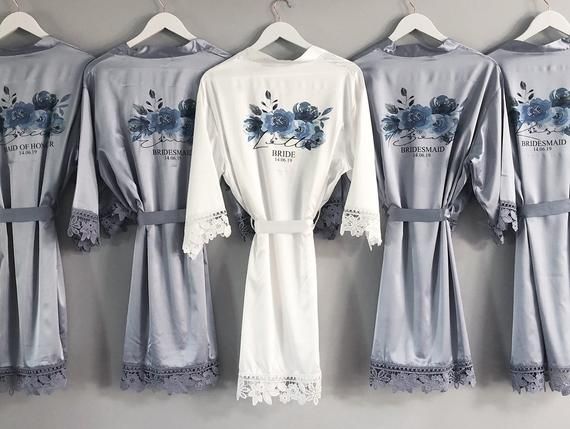 four robes hanging up against a wall with blue flowers and lace on the bottom