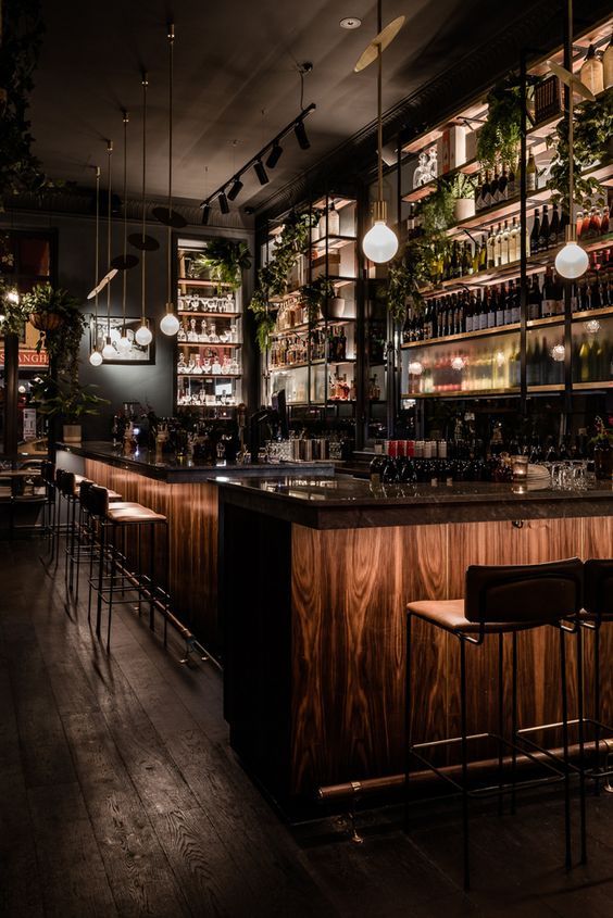 a dimly lit bar with lots of bottles on the shelves and lights hanging from the ceiling