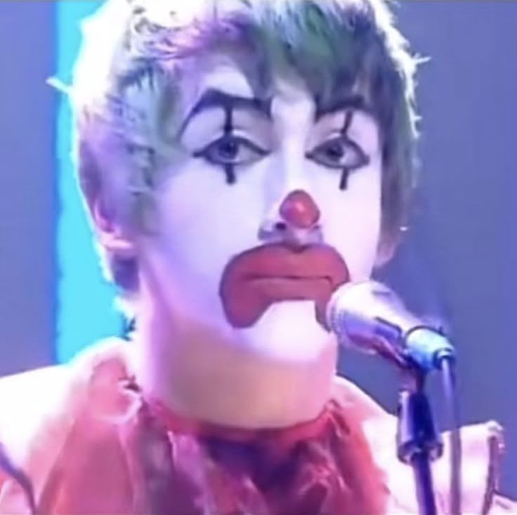 a man with clown makeup on his face holding a microphone