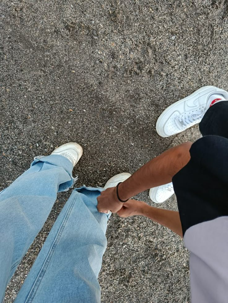 two people standing next to each other with their hands in the air and one person wearing white shoes