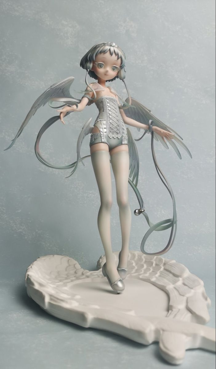 a figurine is standing on top of a white object with wings flying above it