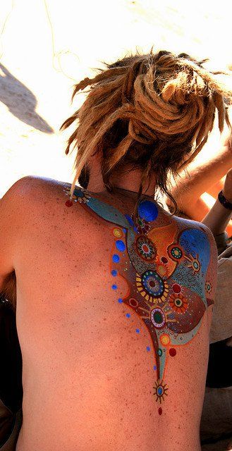 the back of a woman's body covered in colorful designs and tattoos on her chest