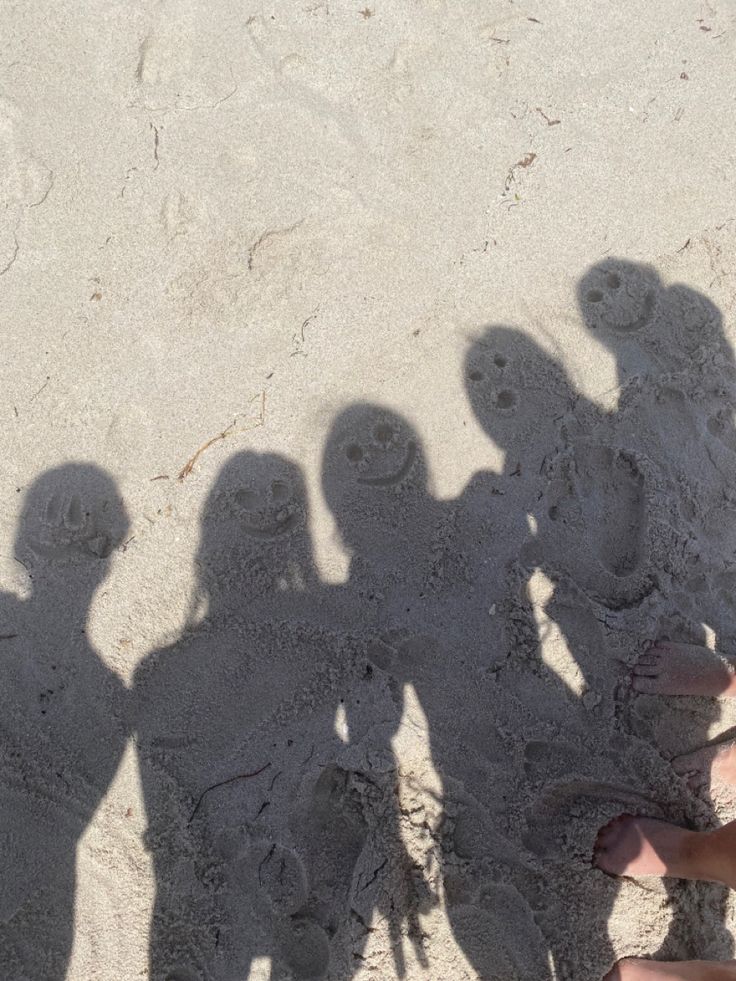 several people standing in the sand with their shadows on them