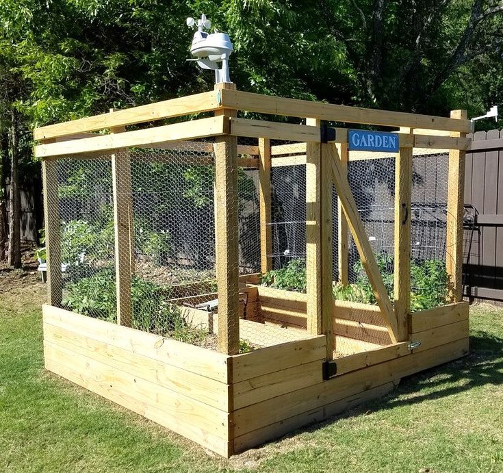 an outdoor garden area with raised wooden planters and fenced in areas around it