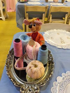 a table topped with lots of spools of thread next to a stuffed animal