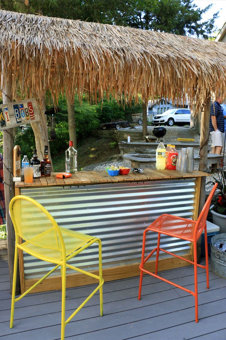 an outdoor bar with two chairs and a straw roof