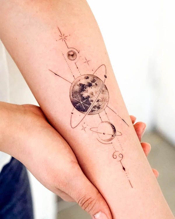 two hands holding each other with tattoos on their arms and the planet in space behind them