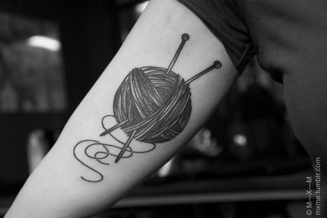 a ball of yarn and knitting needles tattoo on the arm