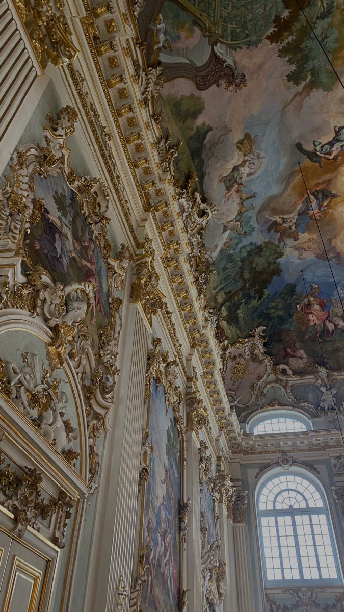 an ornate ceiling with paintings on it in a large room that is painted gold and white