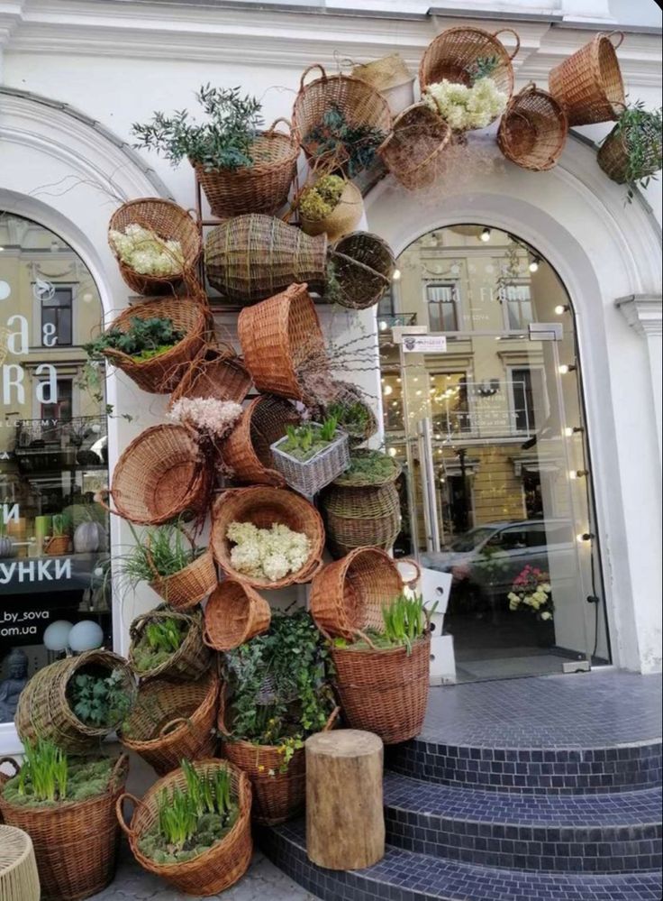 several baskets are stacked on top of each other in front of a building with plants