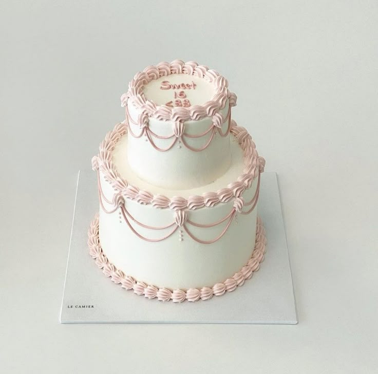 a three tiered cake with pink icing on top and white frosting around the edges